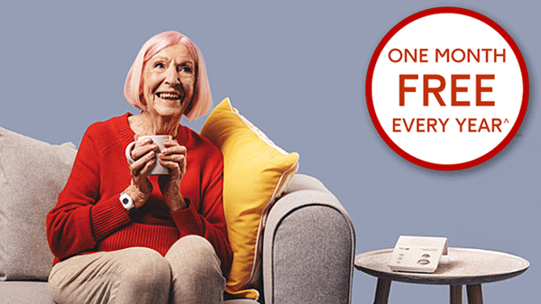 Older lady sitting on couch wearing Age UK personal alarm on wrist